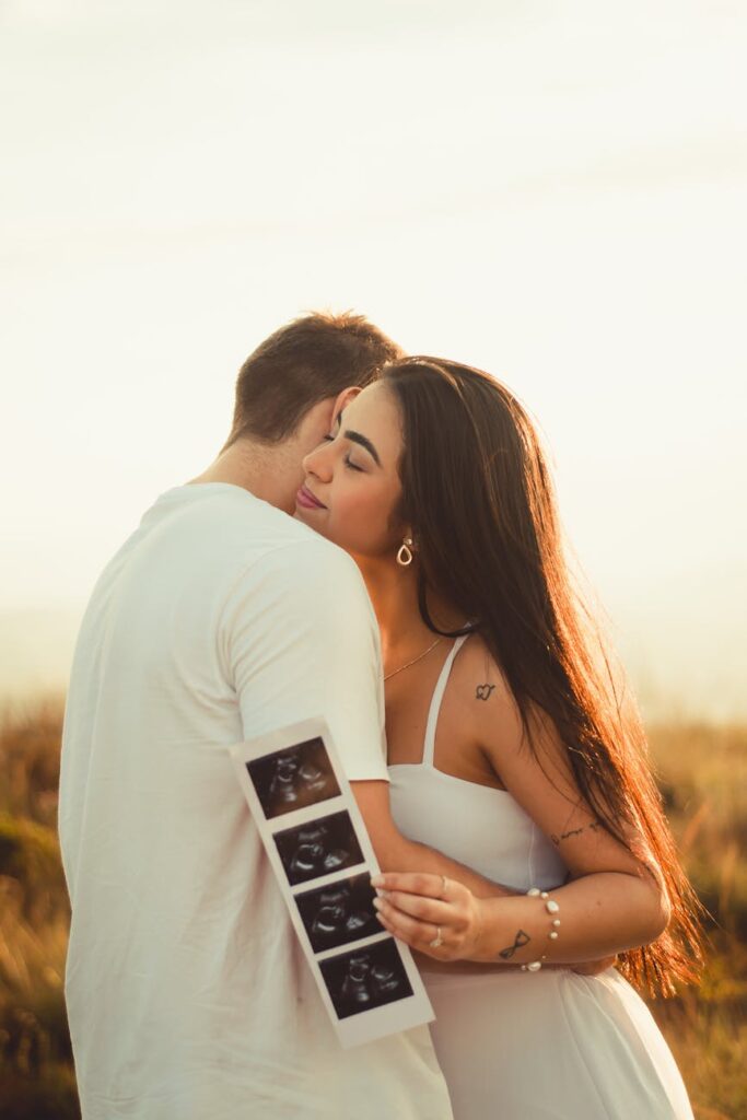 happy couple hugging while woman holding ultrasound pictures of baby